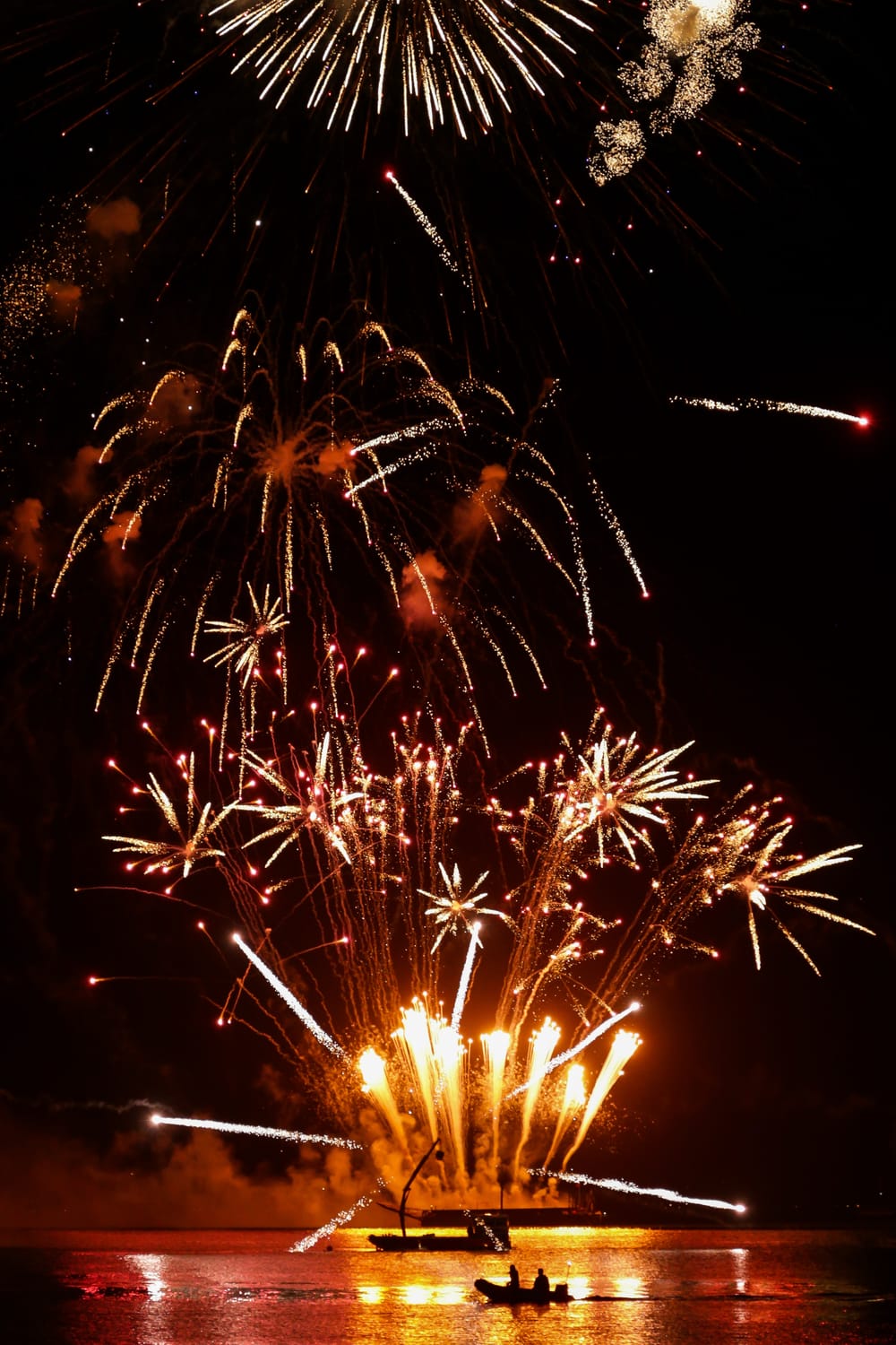 Boat silhouette on the golden sea of fireworks post image