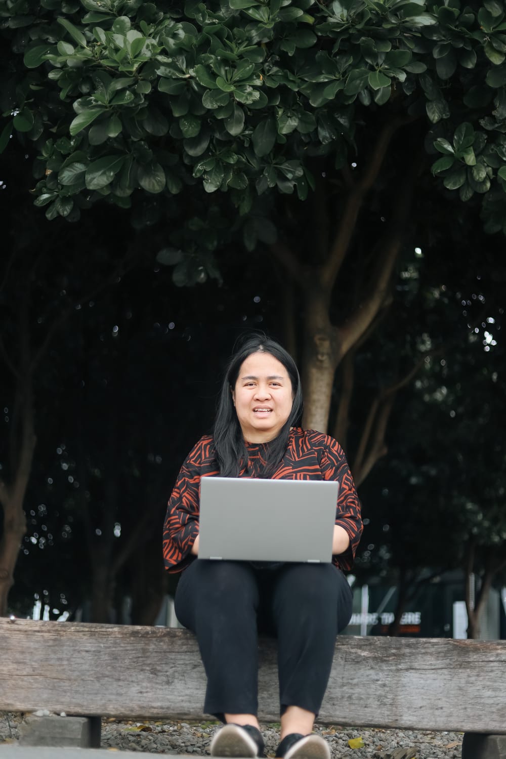 Portrait of woman smiling with laptop outdoors post image