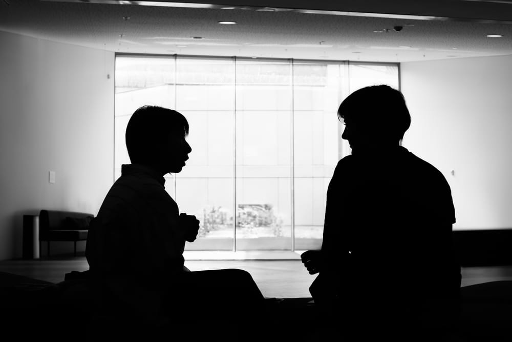 Silhouette of two people in conversation post image