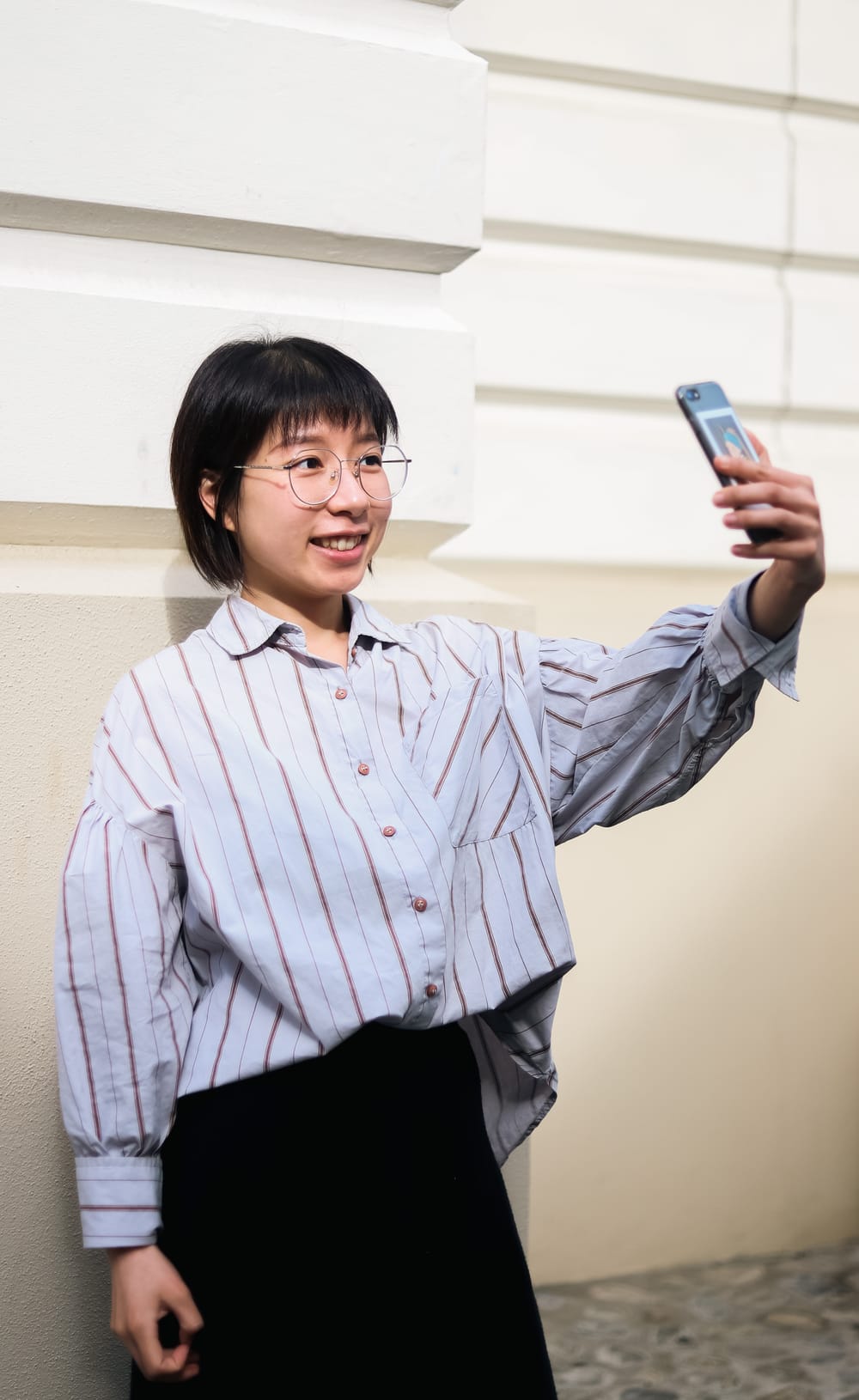 Young woman smiling while taking a selfie outdoors post image