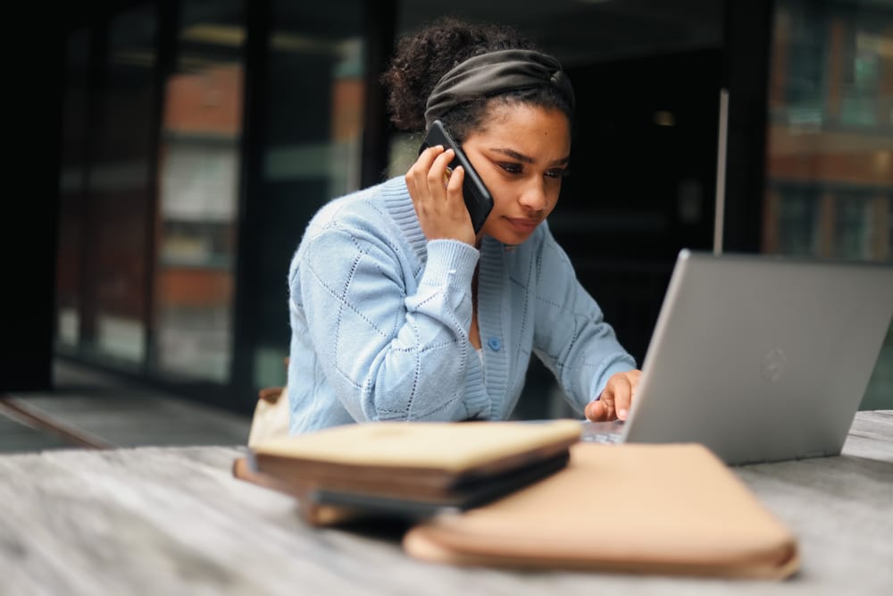 Woman on phone while using laptop post image