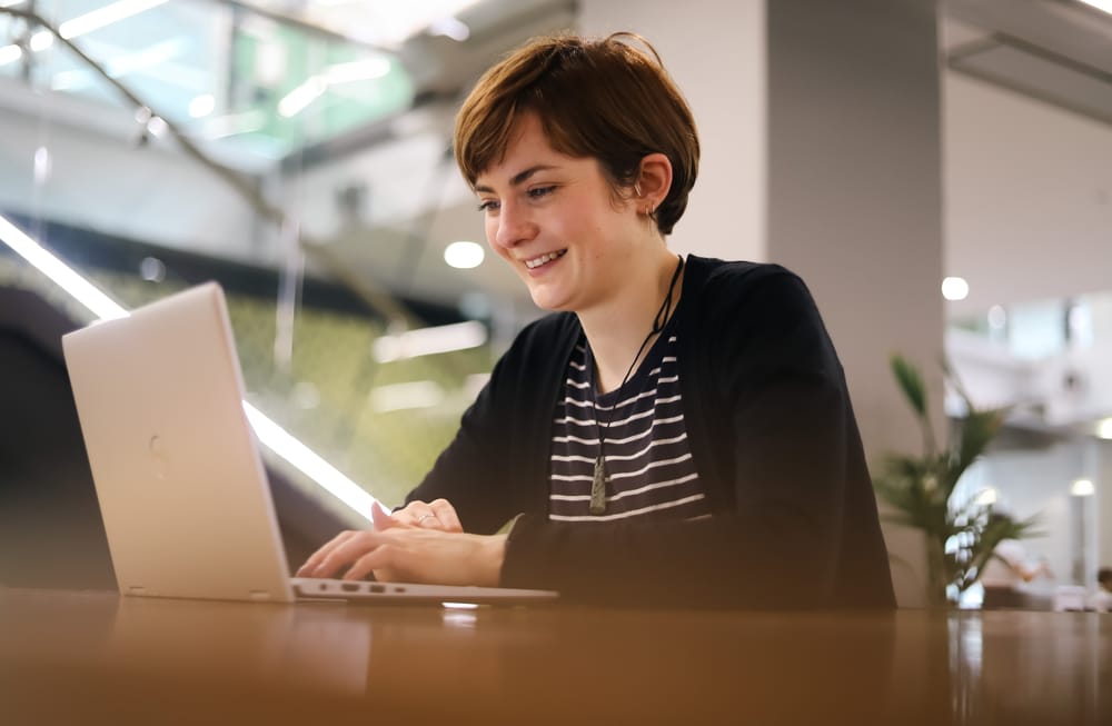 Woman smiling while working on laptop post image