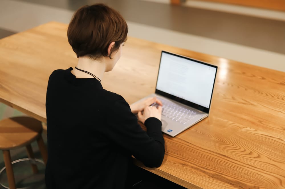 Woman working on laptop at wooden table post image