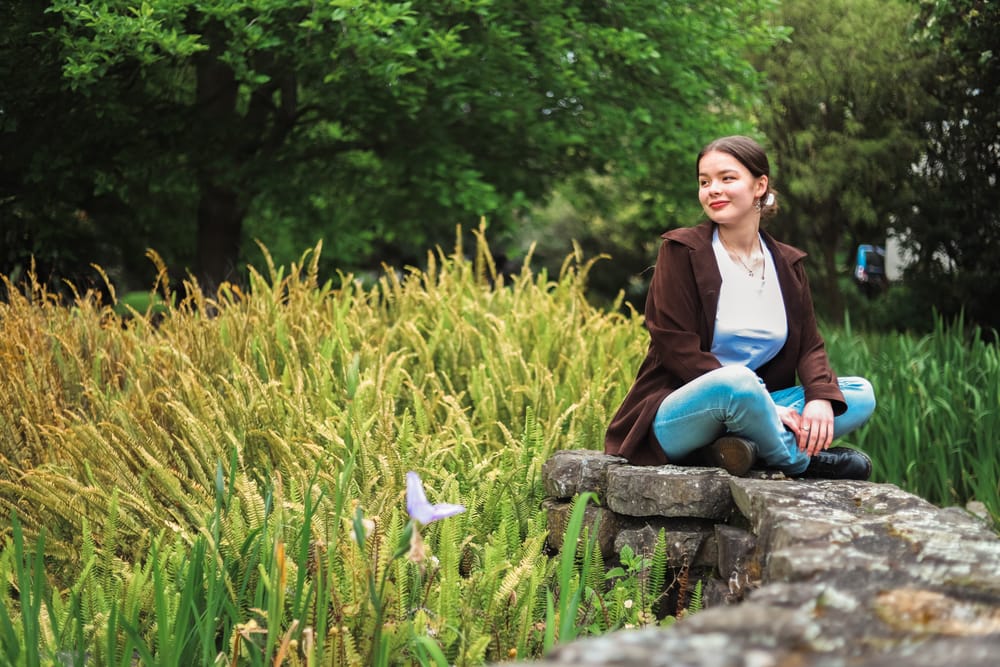 Girl sits on a stone wall post image