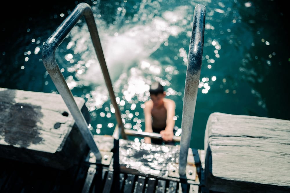 Boy climbing a ladder from sparkling water post image
