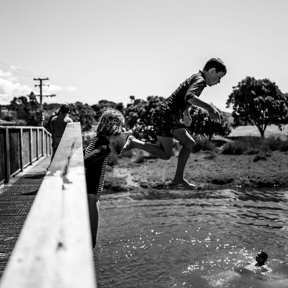 Children jumping from a bridge into the water post image