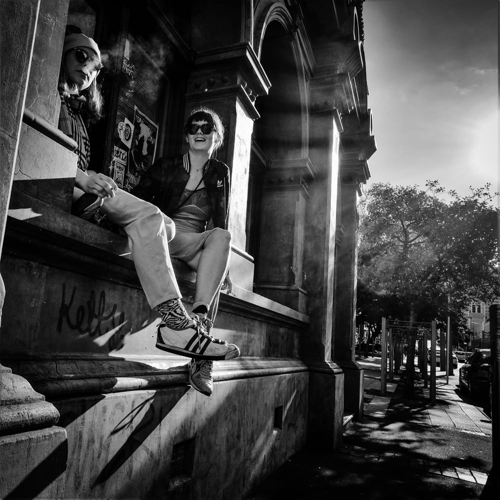 Two women sitting on a stone ledge with graffiti post image
