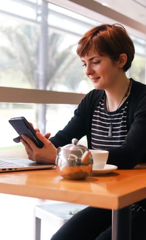Woman smiling at phone in cafe post feature image