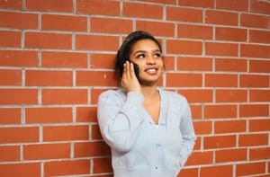 Woman talking on phone by brick wall post feature image