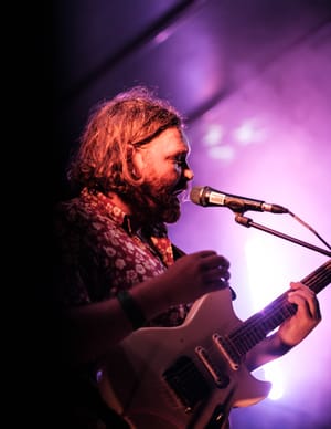 Musician in floral shirt under stage lights post feature image