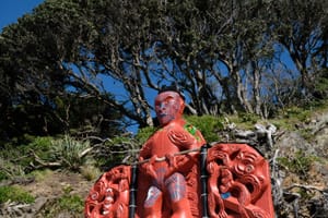 Māori carving with Tā moko in a natural setting post feature image